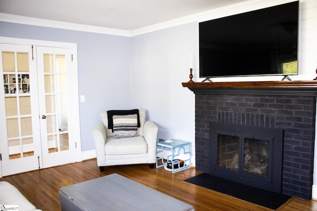 sitting room featuring dark hardwood / wood-style floors, ornamental molding, french doors, and a brick fireplace