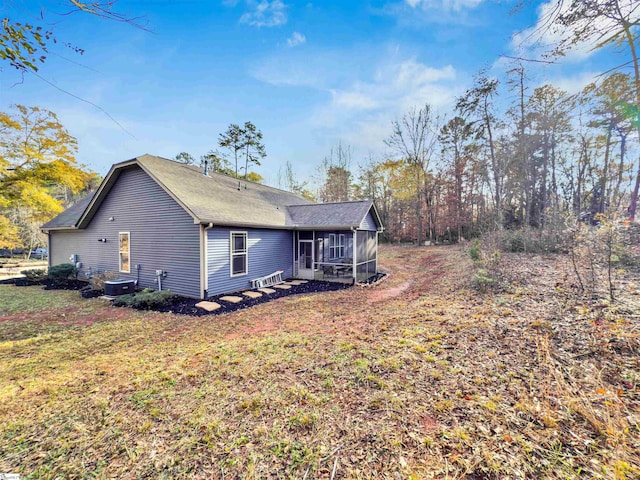 view of side of property with a sunroom, a lawn, and central AC