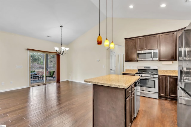 kitchen with decorative light fixtures, appliances with stainless steel finishes, a notable chandelier, a kitchen island, and dark brown cabinetry