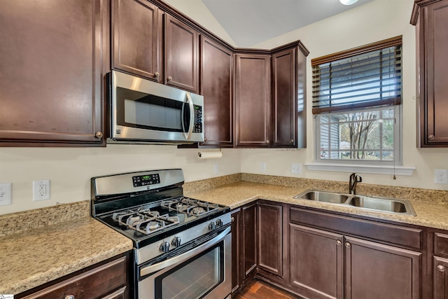 kitchen featuring dark brown cabinets, sink, stainless steel appliances, and vaulted ceiling