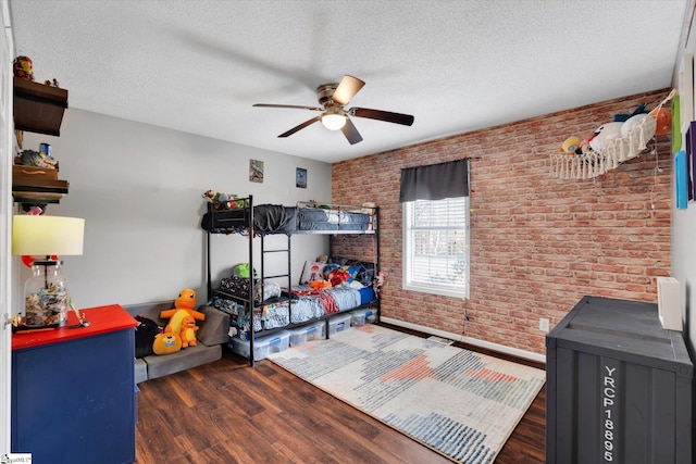 bedroom with a textured ceiling, dark hardwood / wood-style floors, ceiling fan, and brick wall