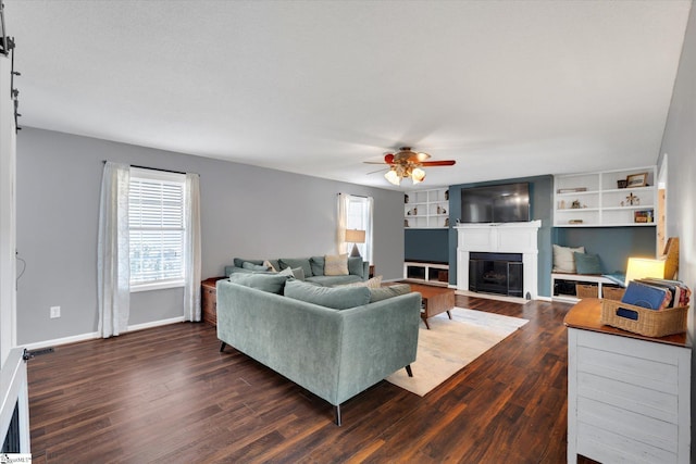 living room with built in shelves, dark hardwood / wood-style flooring, and ceiling fan