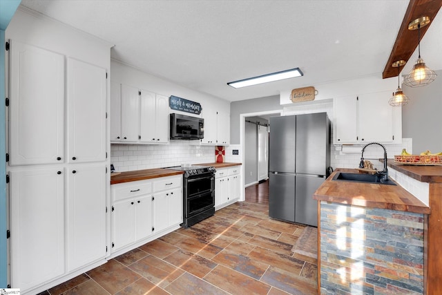 kitchen featuring appliances with stainless steel finishes, tasteful backsplash, sink, white cabinets, and hanging light fixtures