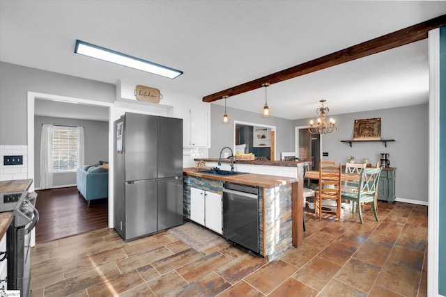 kitchen with sink, stainless steel appliances, beamed ceiling, a notable chandelier, and decorative light fixtures