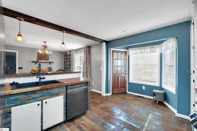 kitchen featuring white cabinets, pendant lighting, stainless steel dishwasher, and sink