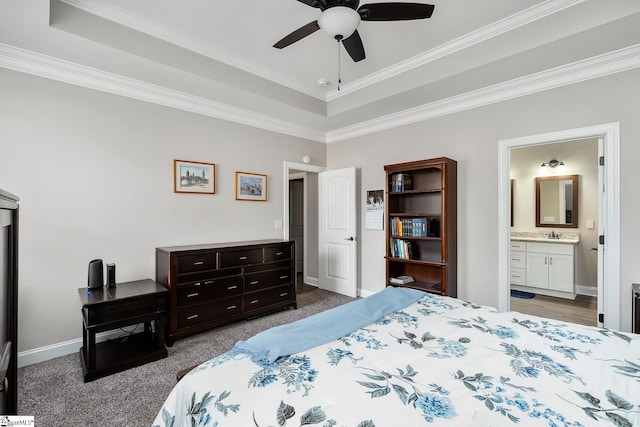 carpeted bedroom with a tray ceiling, ceiling fan, crown molding, sink, and connected bathroom