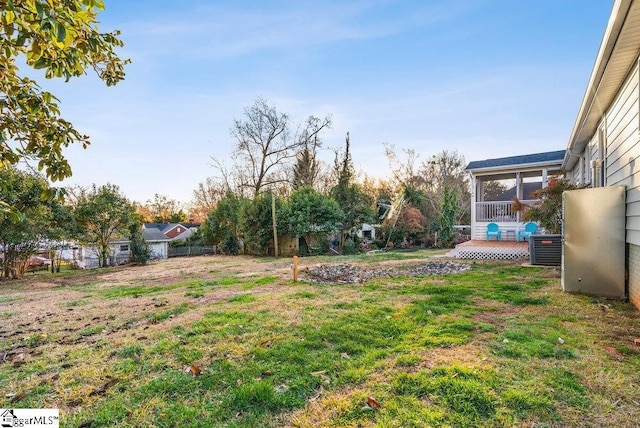 view of yard with a sunroom, a deck, and central AC