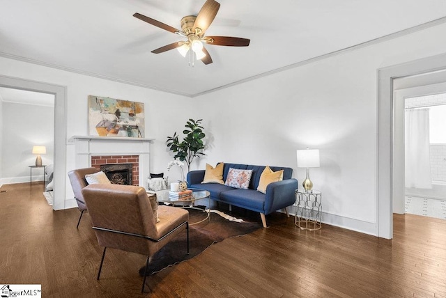 living room with dark hardwood / wood-style floors, ceiling fan, ornamental molding, and a fireplace