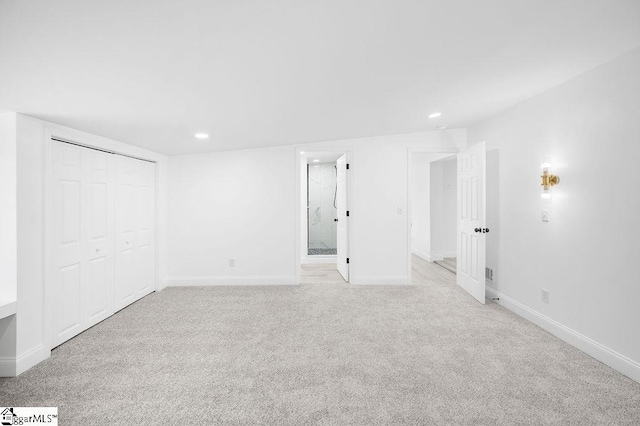 interior space featuring connected bathroom, a closet, and light colored carpet