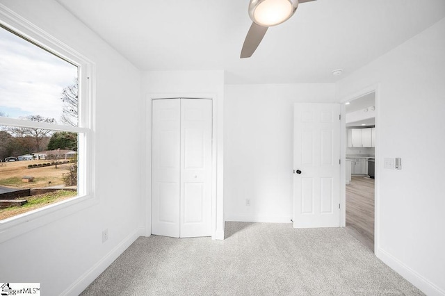 unfurnished bedroom with ceiling fan, light carpet, and a closet