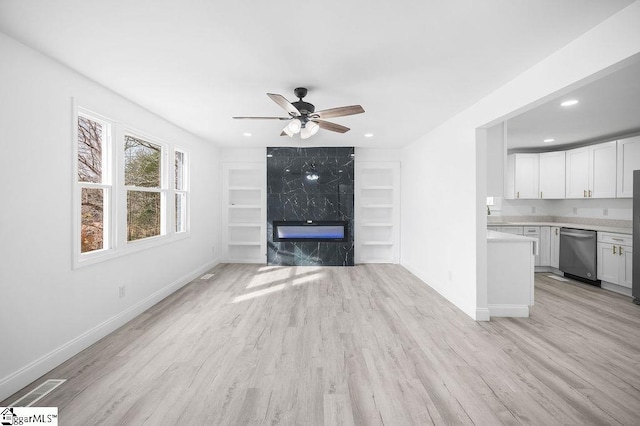 unfurnished living room featuring ceiling fan, light wood-type flooring, and a premium fireplace