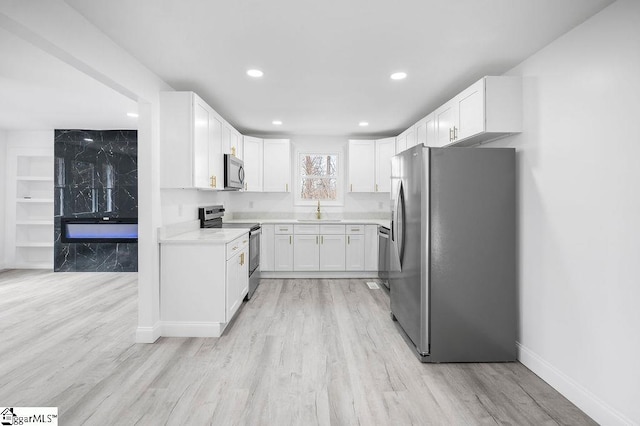 kitchen with light wood-type flooring, stainless steel appliances, white cabinetry, and sink