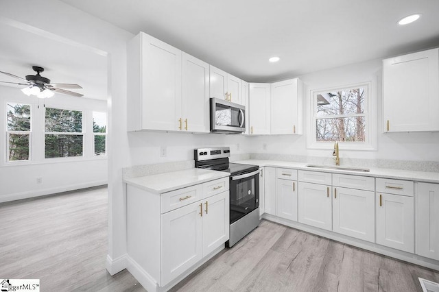 kitchen featuring white cabinets, light hardwood / wood-style floors, sink, and appliances with stainless steel finishes