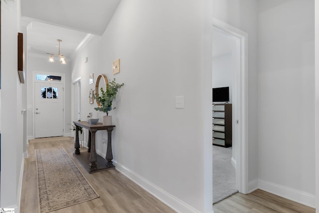 entryway featuring a chandelier, light wood-type flooring, and crown molding