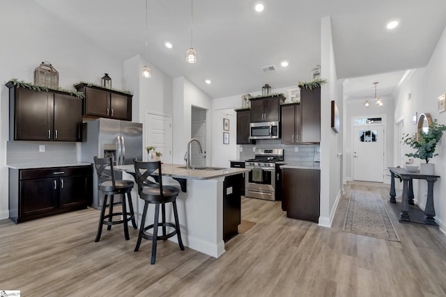 kitchen with decorative backsplash, sink, stainless steel appliances, and hanging light fixtures