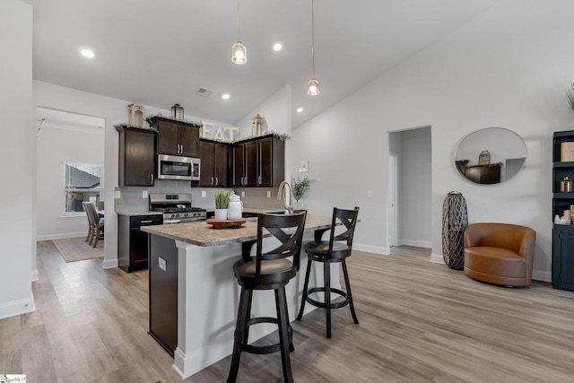 kitchen with high vaulted ceiling, appliances with stainless steel finishes, tasteful backsplash, decorative light fixtures, and dark brown cabinets