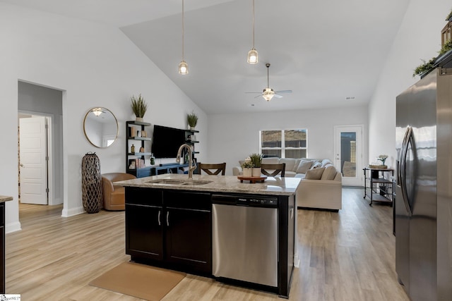 kitchen featuring light stone countertops, sink, hanging light fixtures, an island with sink, and appliances with stainless steel finishes