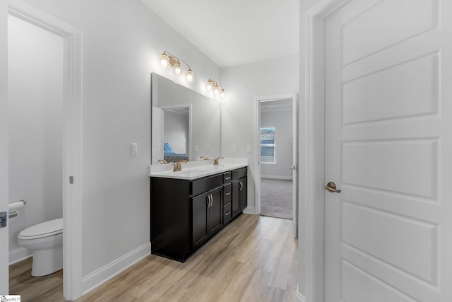 bathroom with hardwood / wood-style flooring, vanity, and toilet