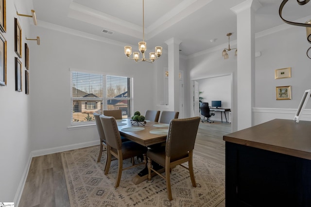 dining area with a chandelier, a raised ceiling, light hardwood / wood-style flooring, and ornamental molding