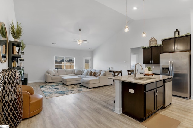 kitchen featuring dark brown cabinetry, stainless steel appliances, sink, decorative light fixtures, and an island with sink