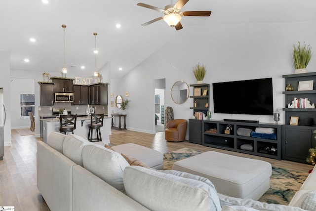 living room featuring ceiling fan, light hardwood / wood-style floors, and high vaulted ceiling