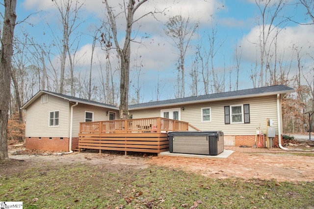 back of property with a wooden deck and a hot tub