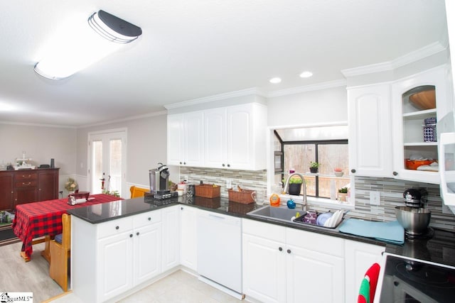 kitchen featuring backsplash, white dishwasher, sink, white cabinetry, and kitchen peninsula