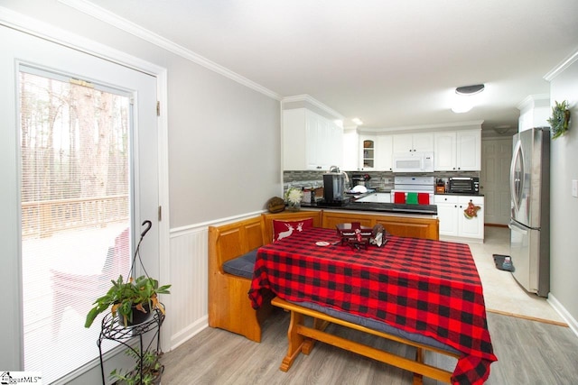 kitchen featuring white cabinets, stainless steel fridge, light wood-type flooring, and ornamental molding