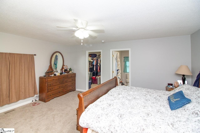 bedroom featuring a walk in closet, ensuite bathroom, ceiling fan, carpet floors, and a closet