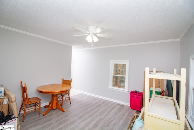 dining space with a textured ceiling, light hardwood / wood-style floors, and crown molding