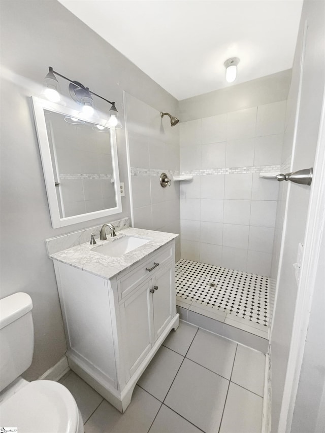 bathroom with tiled shower, vanity, toilet, and tile patterned flooring