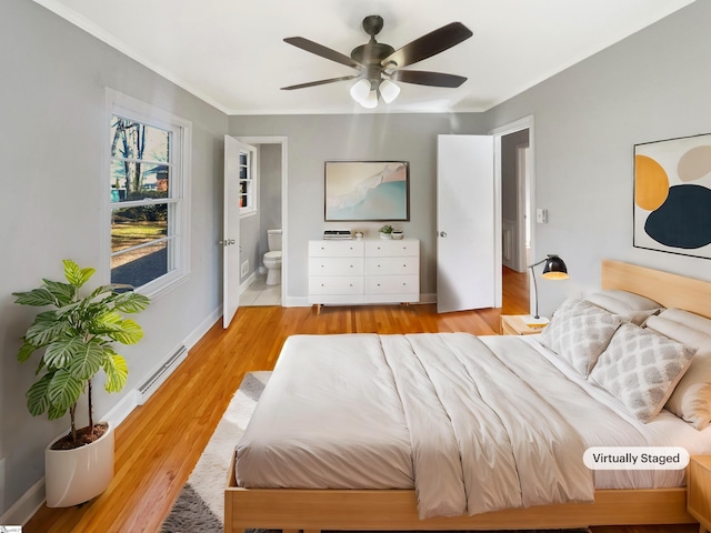 bedroom with connected bathroom, light hardwood / wood-style flooring, ceiling fan, and a baseboard heating unit