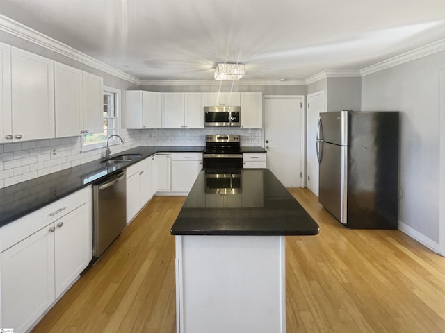 kitchen with white cabinets, sink, decorative light fixtures, a kitchen island, and stainless steel appliances