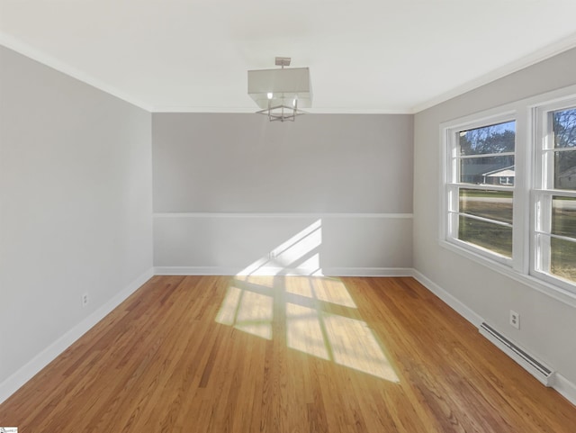 spare room with light wood-type flooring, a baseboard radiator, and ornamental molding