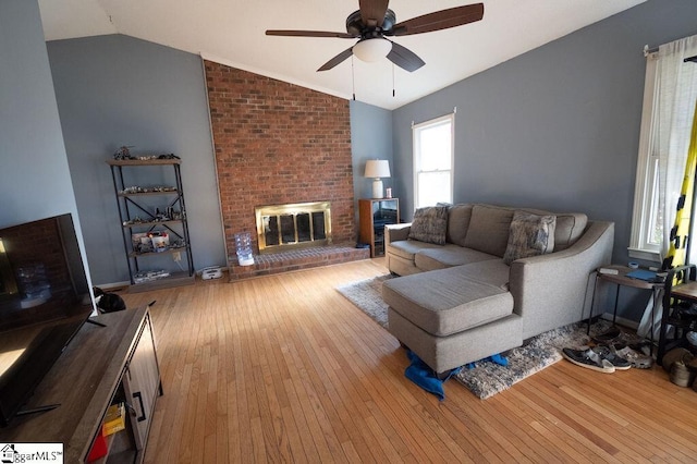 living room featuring a brick fireplace, ceiling fan, light hardwood / wood-style flooring, and vaulted ceiling