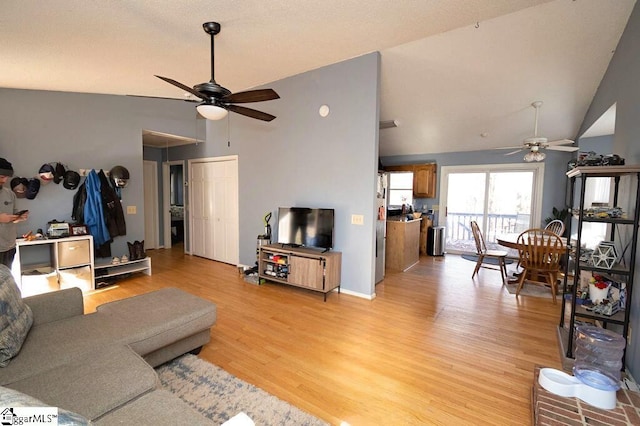 living room featuring ceiling fan, light hardwood / wood-style floors, and lofted ceiling