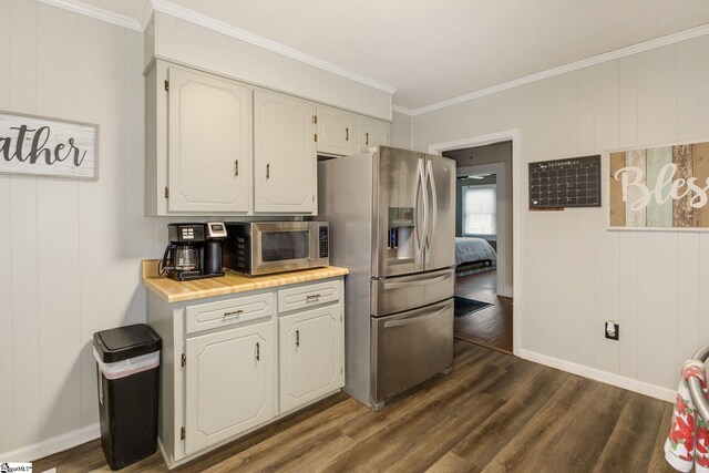 kitchen with wooden walls, ornamental molding, appliances with stainless steel finishes, dark hardwood / wood-style flooring, and white cabinetry