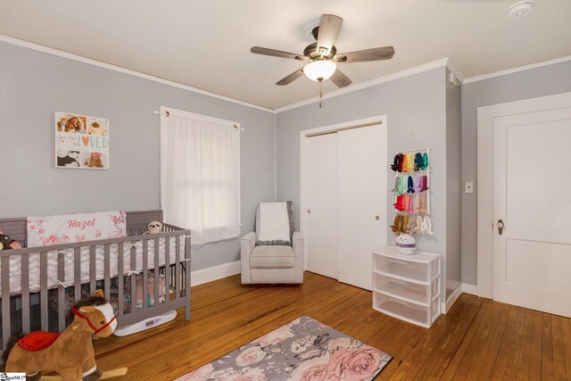 bedroom with ceiling fan, ornamental molding, a crib, and hardwood / wood-style flooring