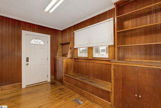 foyer with wood walls, hardwood / wood-style floors, and crown molding