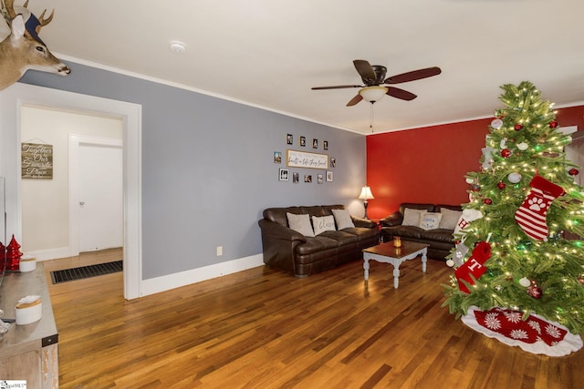 living room featuring wood-type flooring, ceiling fan, and crown molding