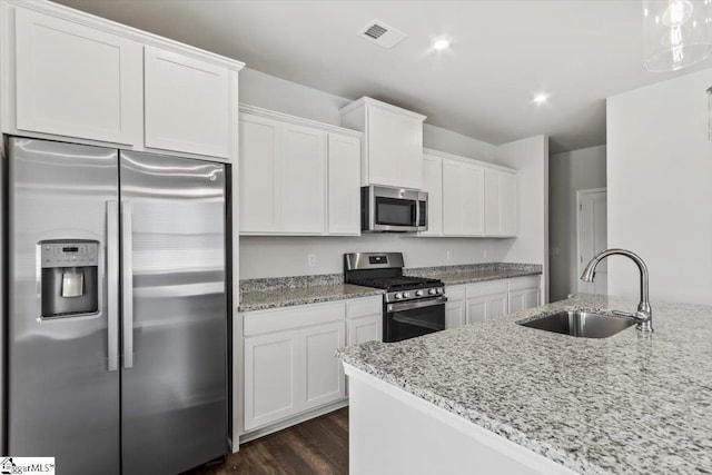 kitchen with light stone countertops, sink, white cabinets, and stainless steel appliances