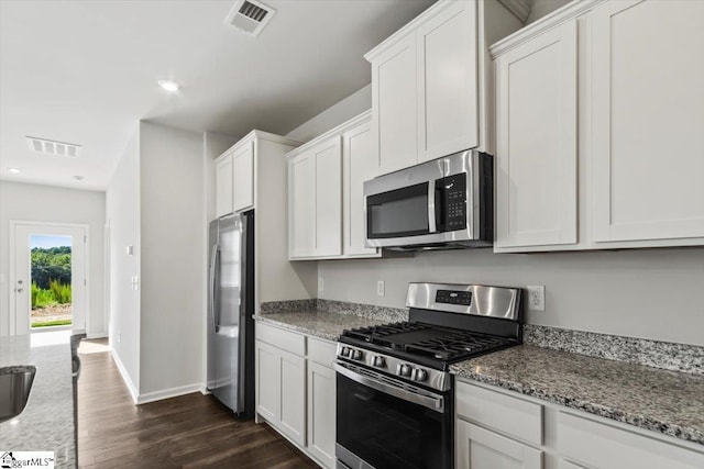 kitchen featuring light stone countertops, appliances with stainless steel finishes, white cabinetry, and dark wood-type flooring