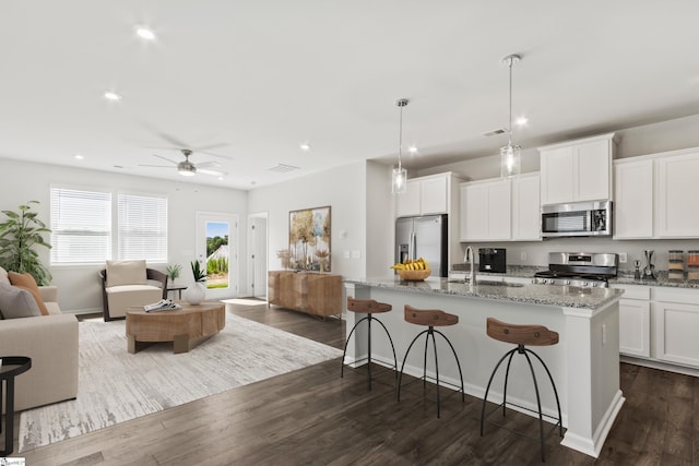 kitchen with a center island with sink, decorative light fixtures, white cabinetry, and stainless steel appliances