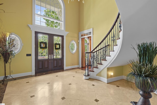 tiled foyer featuring french doors and a towering ceiling