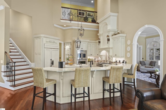 kitchen featuring kitchen peninsula, a kitchen breakfast bar, a towering ceiling, and hanging light fixtures