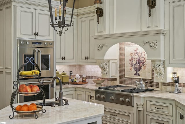 kitchen featuring cream cabinets, sink, decorative backsplash, light stone countertops, and stainless steel gas cooktop