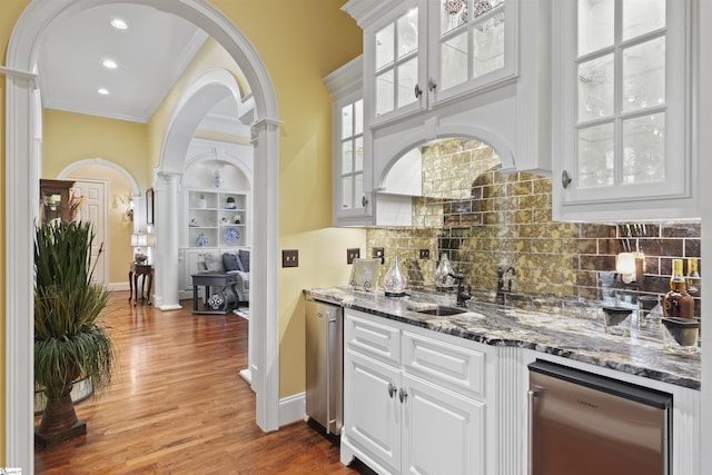 bar featuring white cabinets, dark hardwood / wood-style flooring, ornamental molding, and dark stone countertops