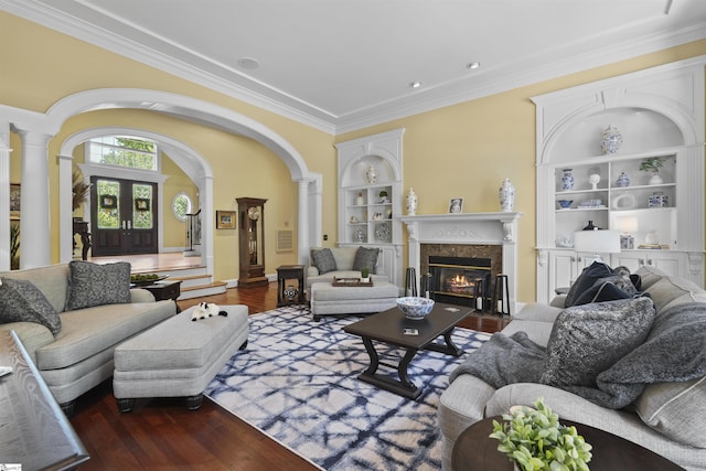 living room with built in shelves, ornate columns, and dark wood-type flooring