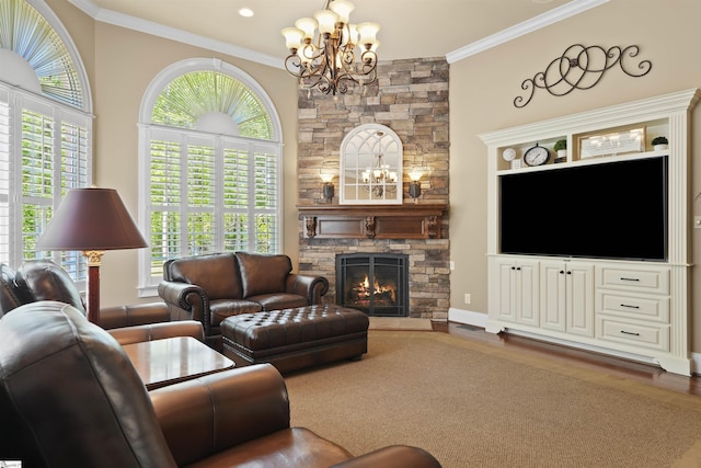 living room with a stone fireplace, ornamental molding, a healthy amount of sunlight, and an inviting chandelier