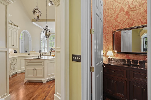 bathroom with vanity, vaulted ceiling, crown molding, a notable chandelier, and hardwood / wood-style floors